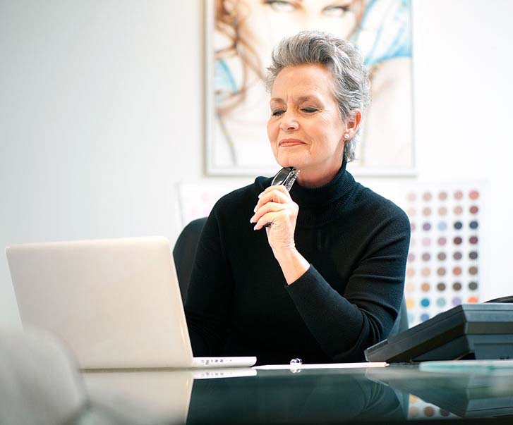 Woman sitting at her desk using her laptop in a small business setting