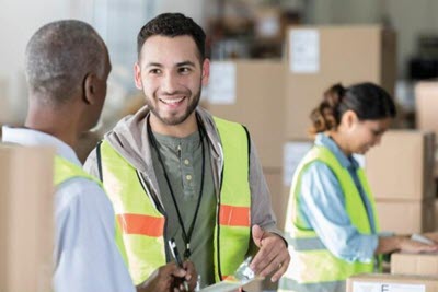 three employees wearing safety vests having discussion